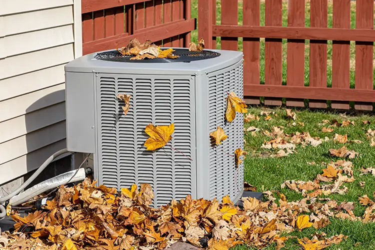 HVAC system outdoors surrounded by fall leaves