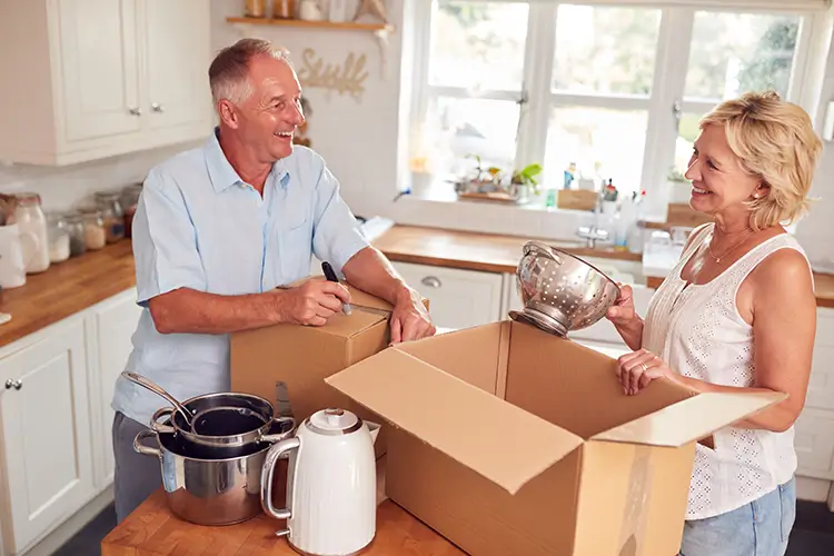Senior couple downsizing and packing items into moving boxes