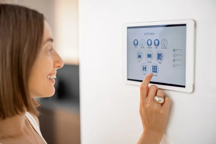 Woman using a panel on her wall with smart kitchen and light features