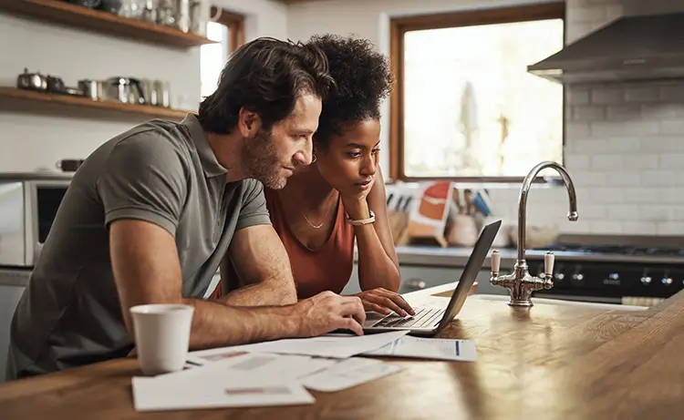 Couple researching on laptop in their kitchen